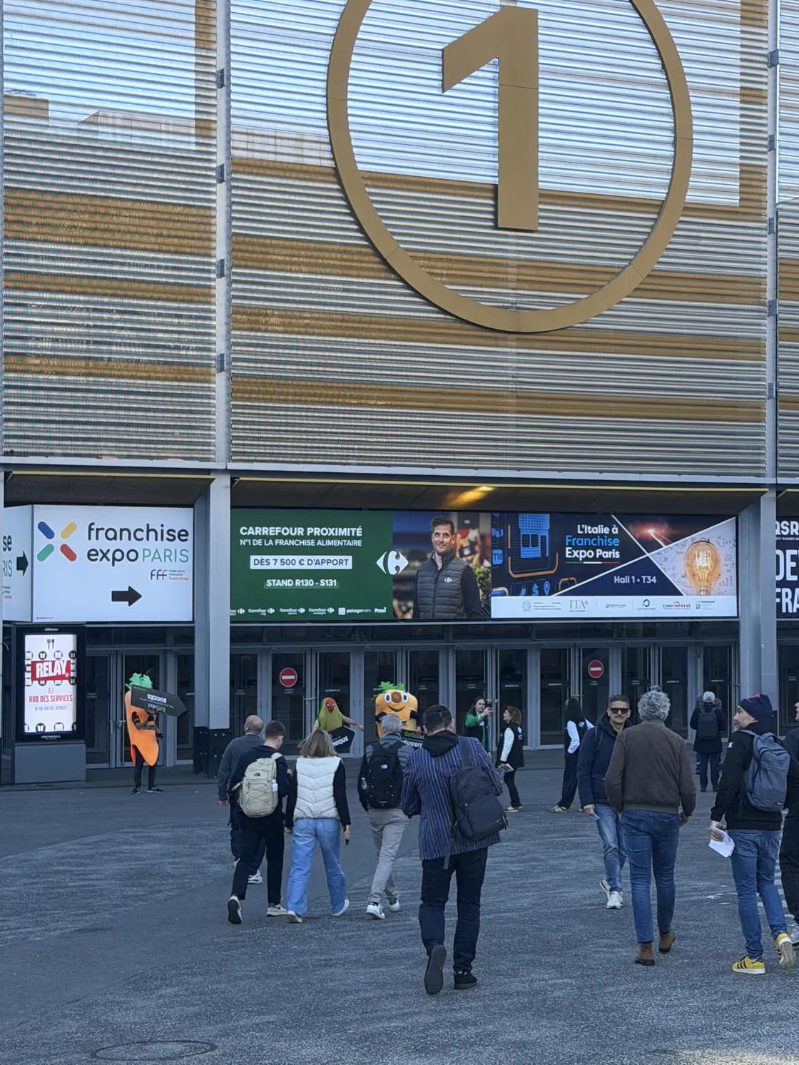 Bandeau de recrutement Carrefour Proximité en façade du hall 1 à Franchise Expo Paris, avec le portrait d'un franchisé